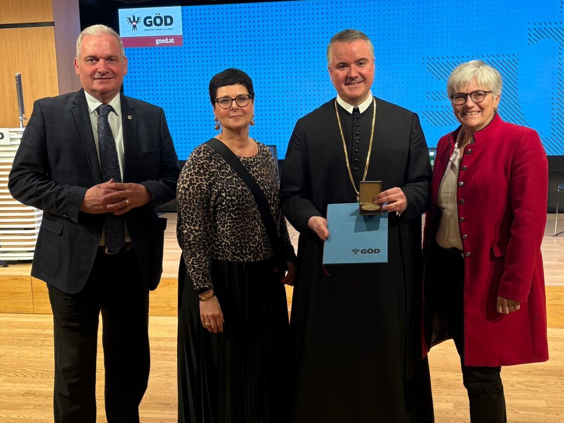 Direktorin mit zwei Lehrern und einer Lehrerin mit Auszeichnung Johannes-Messner Medaille, in die Kamera blickend.