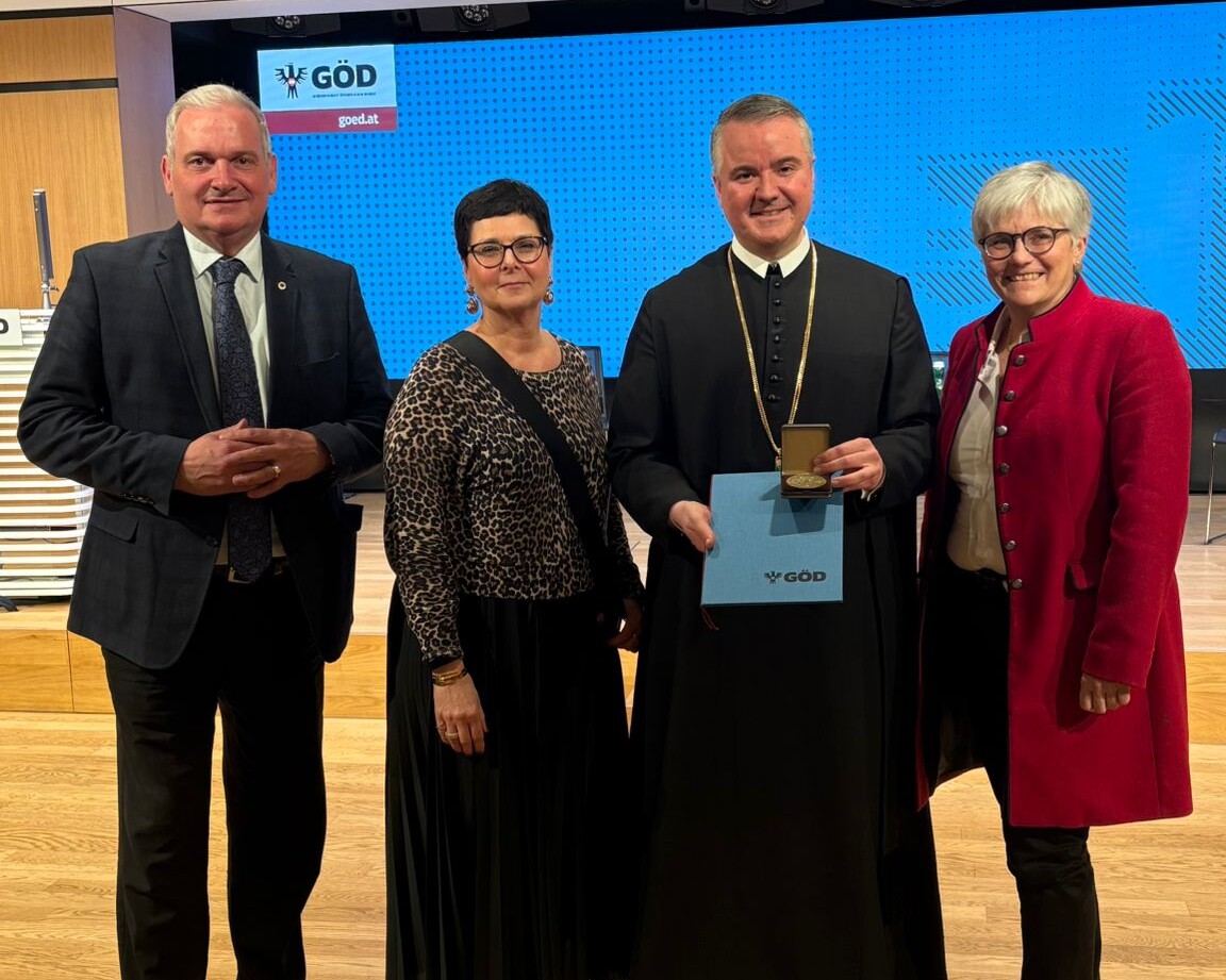 Direktorin mit zwei Lehrern und einer Lehrerin mit Auszeichnung Johannes-Messner Medaille, in die Kamera blickend.