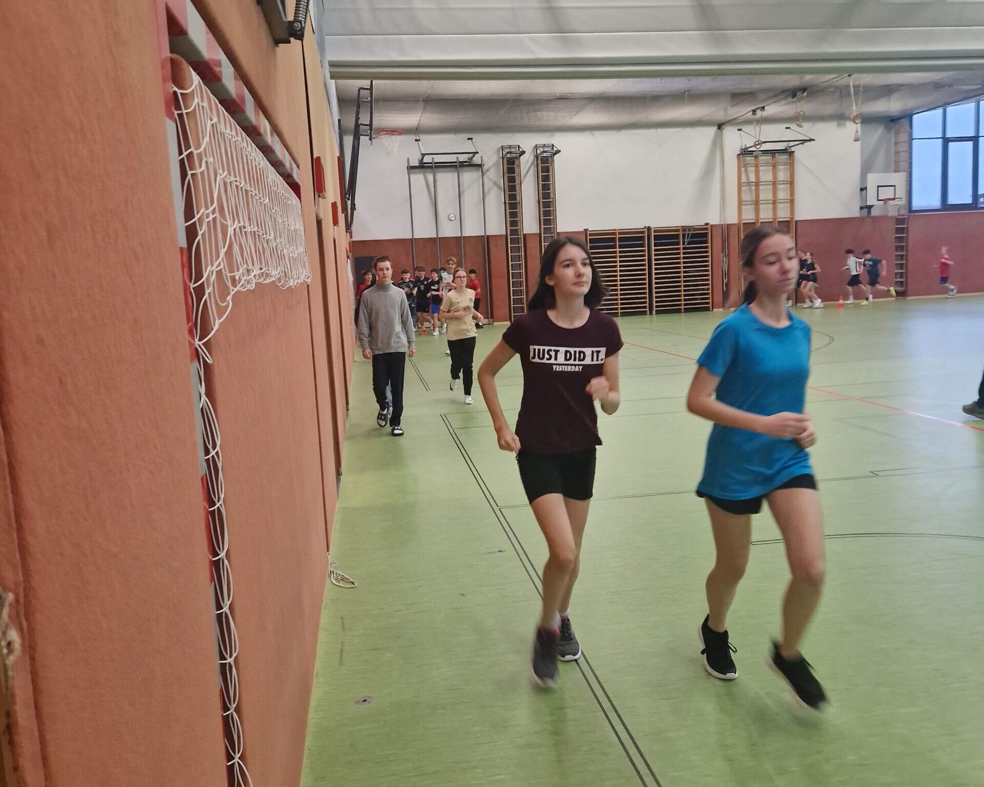 Mehrere Schüler*innen laufend im Turnsaal.
