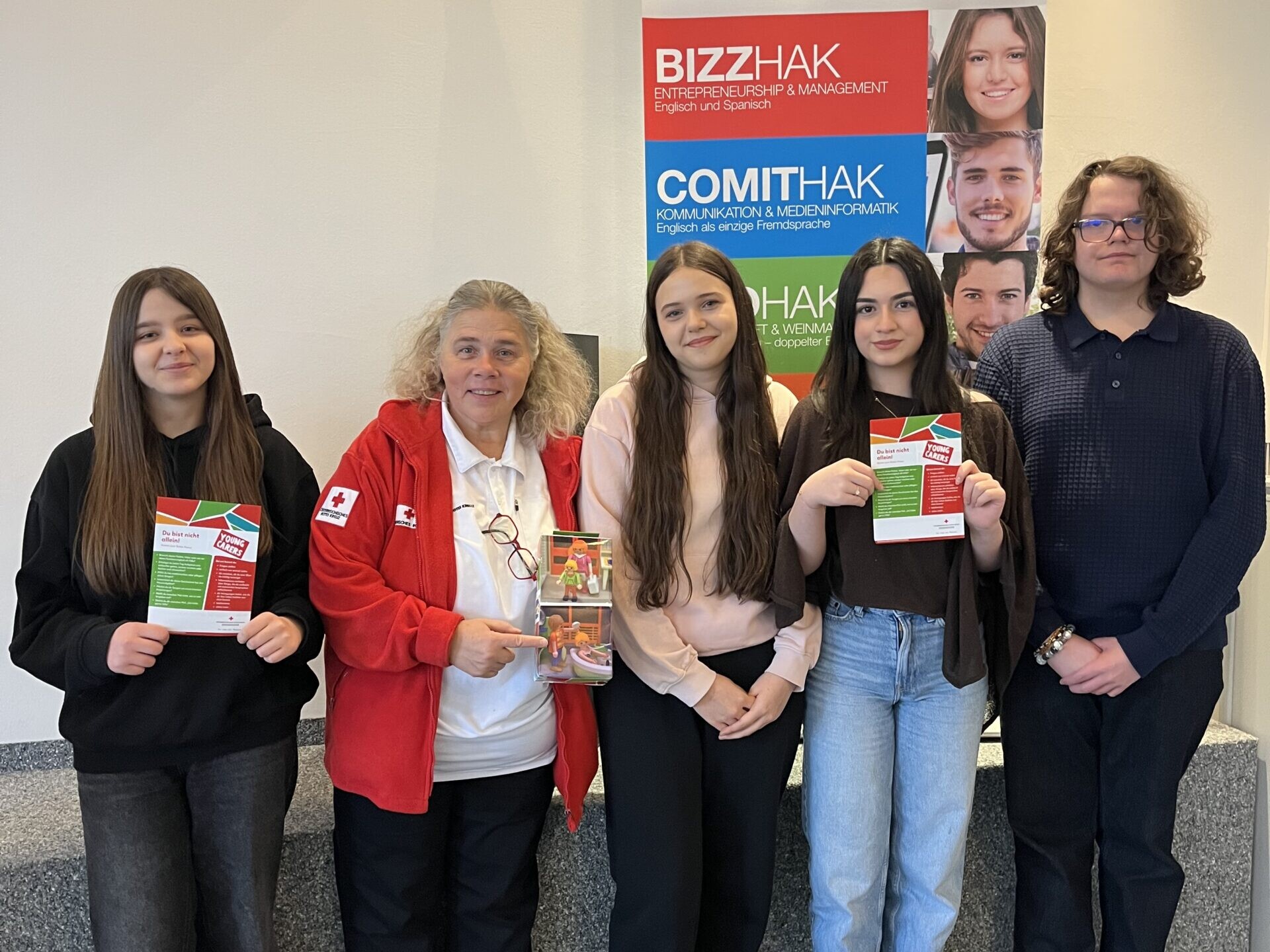 3 Schülerinnen, 1 Schüler und eine Frau vom Roten Kreuz lächeln in die Kamera.