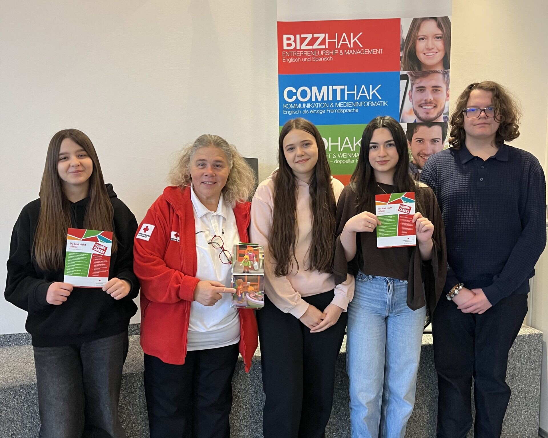 3 Schülerinnen, 1 Schüler und eine Frau vom Roten Kreuz lächeln in die Kamera.