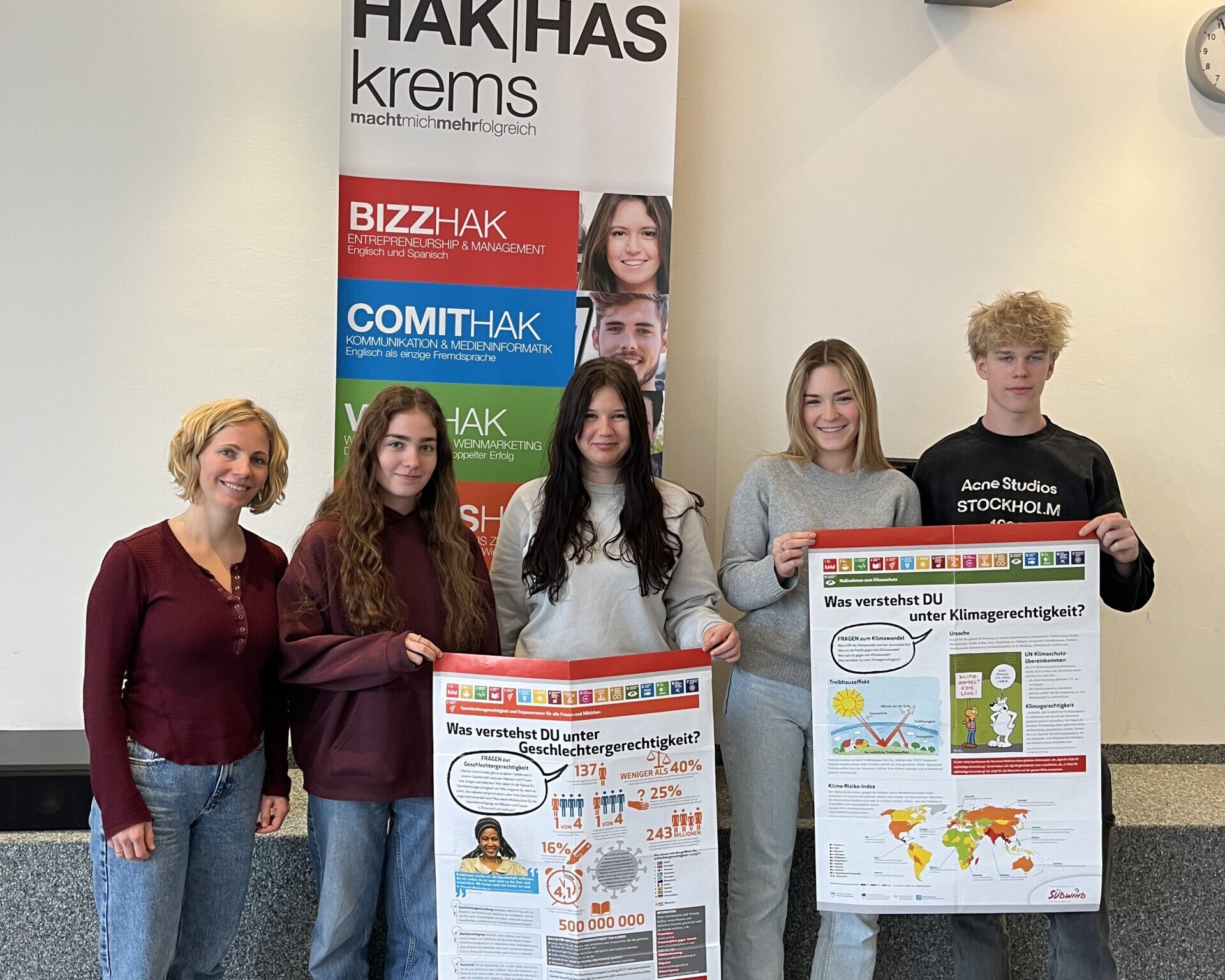 1 Betreuerin, 3 Schülerinnen und 1 Schüler lächeln in die Kamera, die Schüler:innen halten 2 NGO's Plakate.