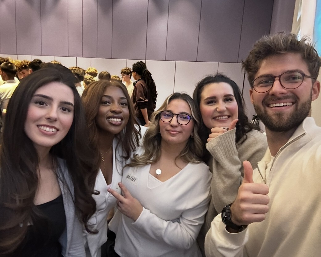 3 Schülerinnen und ein Coach lächeln in die Kamera.