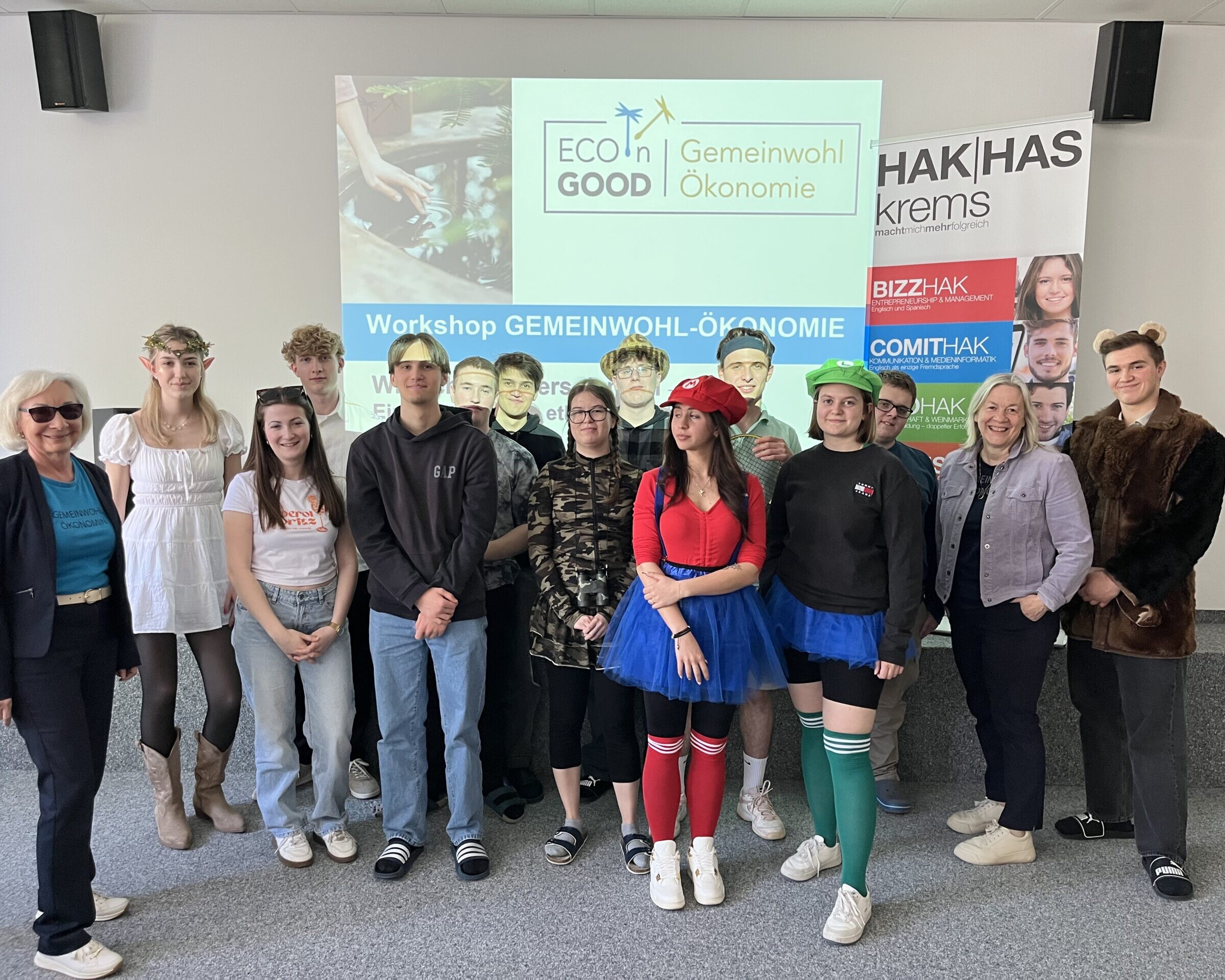 Gruppenbild mit Schüler:innen und Betreuerinnen, hinter ihnen ein Bild an die Wand gebeamt mit 