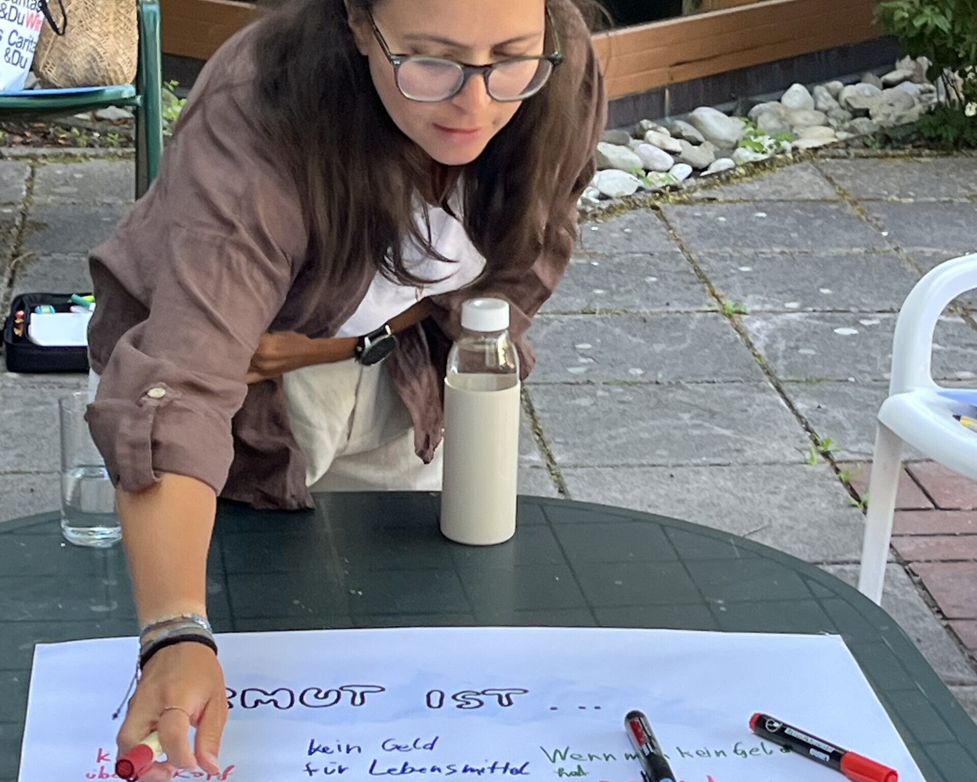 Frau über ein auf Tisch liegendem Plakat gebeugt.
