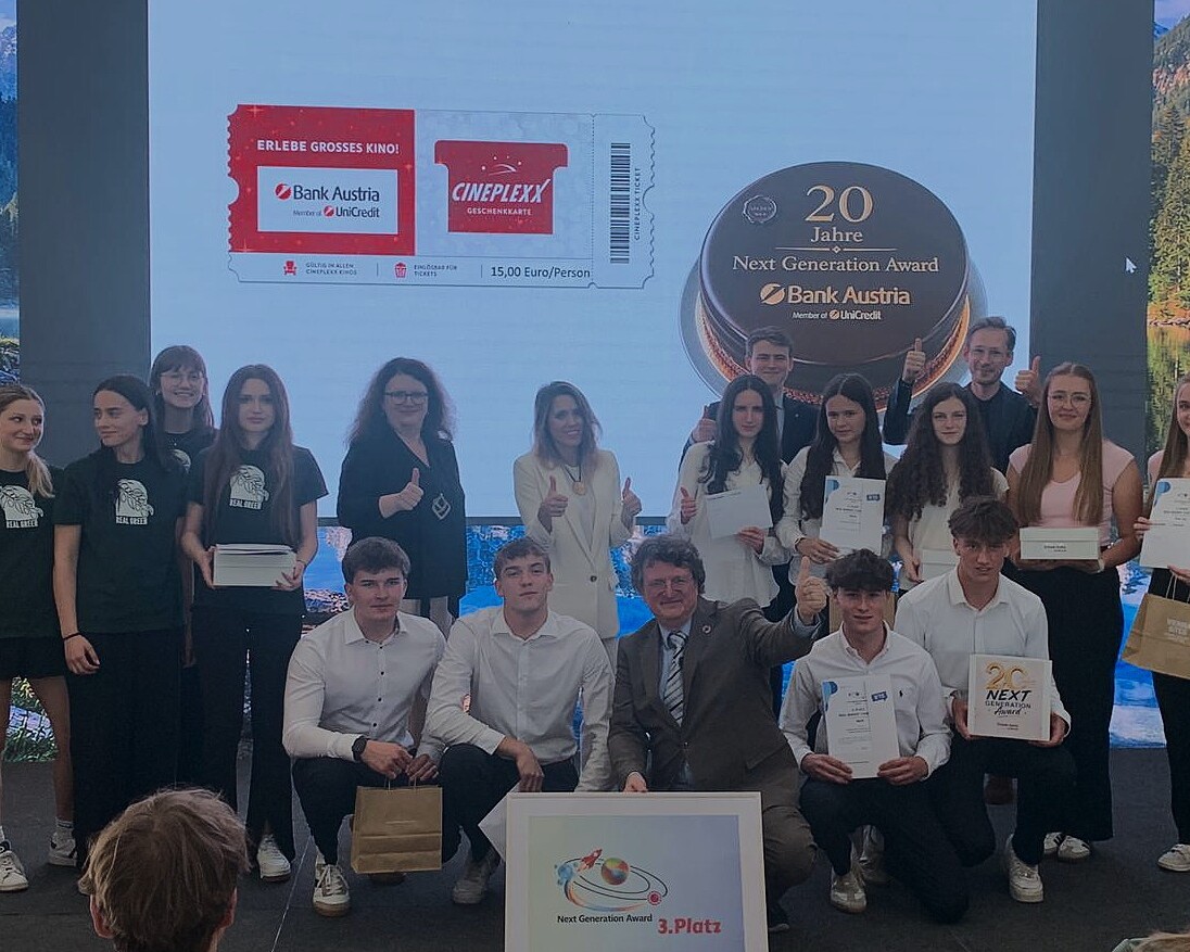 Gruppenfoto bei der Preisverleihung des Next Generation Award: Jugendliche und Erwachsene präsentieren Urkunden, Preise und eine Auszeichnung für den 3. Platz auf einer Bühne.