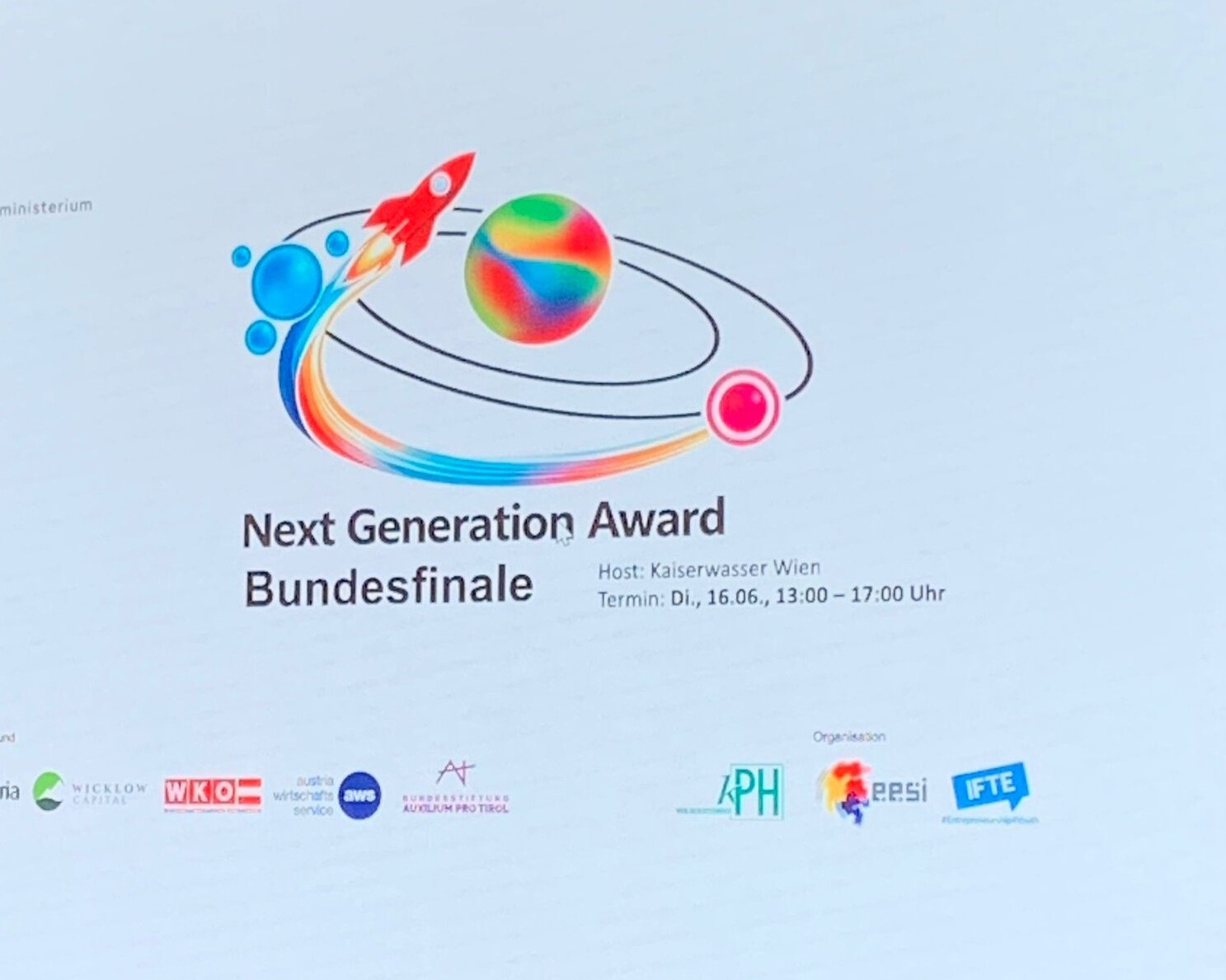 Präsentationsfolie zum „Next Generation Award Bundesfinale“ mit buntem Raketenlogo sowie Angaben zu Ort und Termin der Veranstaltung.