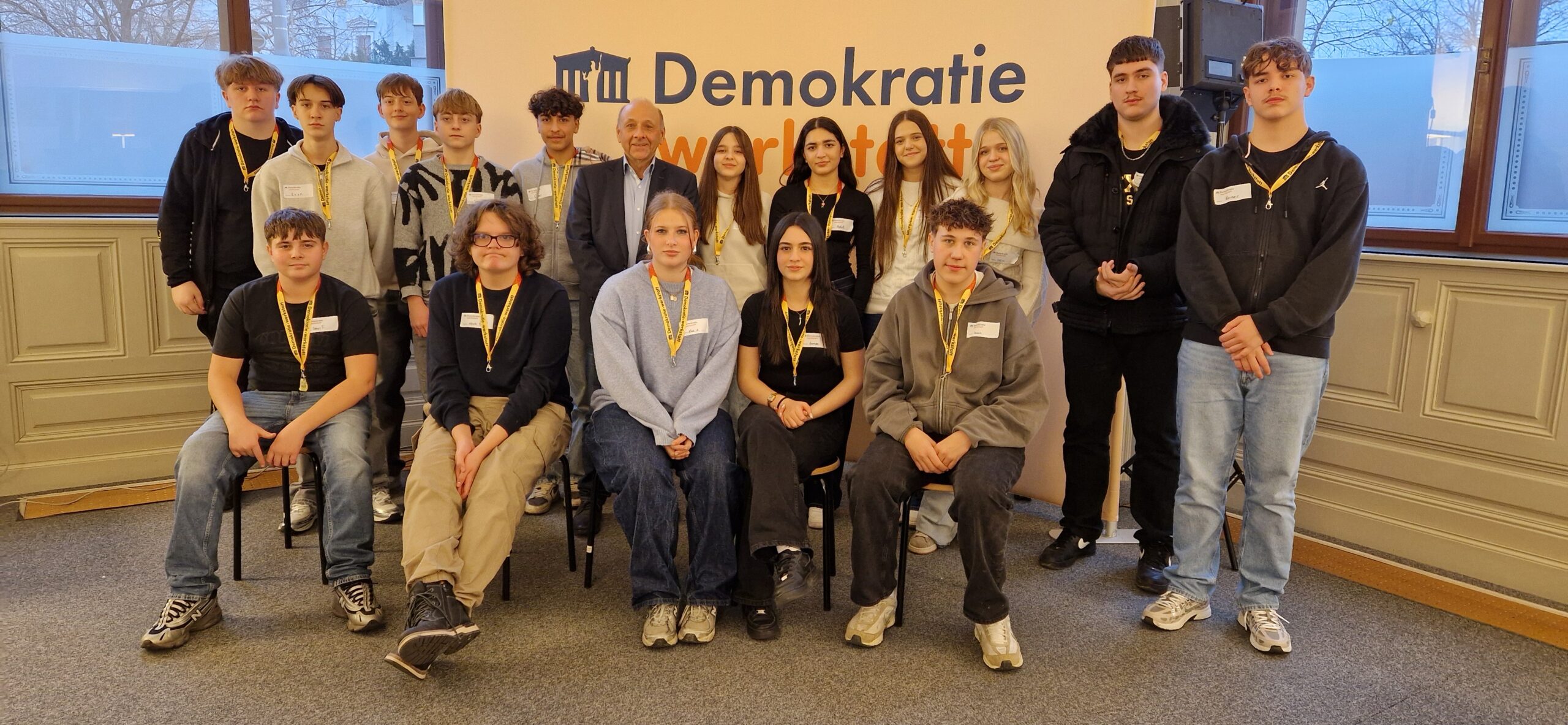 15 Schüler*innen mit ORF-Journalisten Dr. Robert Stoppacher bei der Demokratiewerkstatt, direkt in die Kamera blickend.