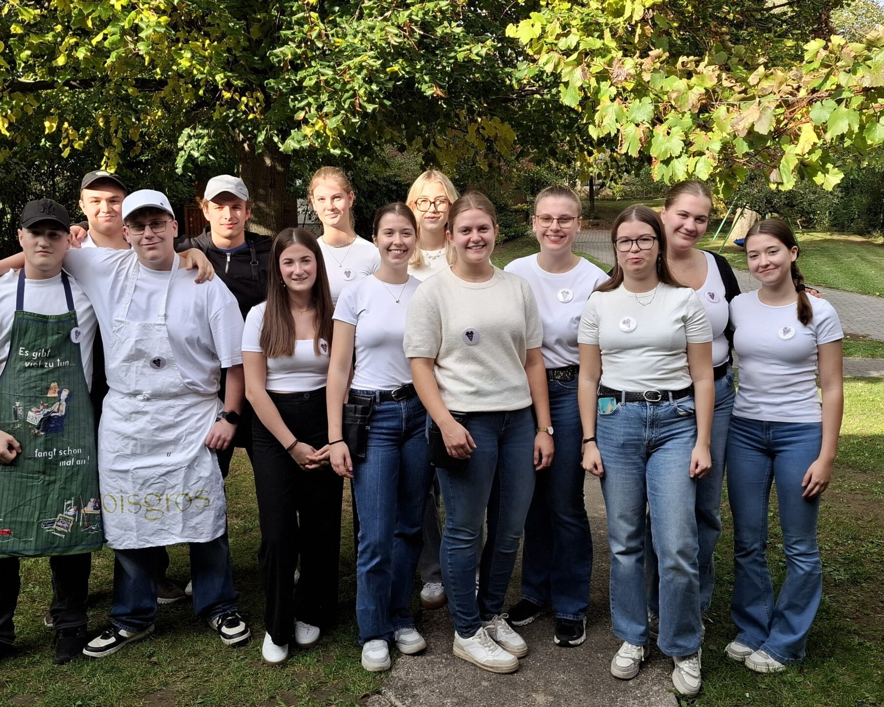 Eine Gruppe von Jugendlichen steht draußen gemeinsam für ein Gruppenfoto im Garten.
