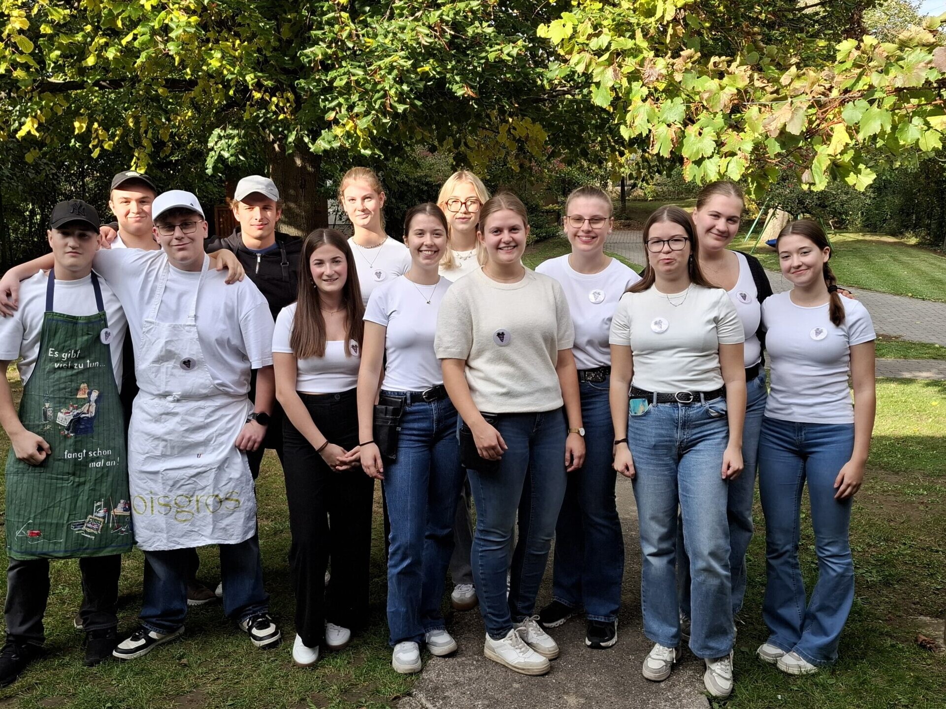 Eine Gruppe von Jugendlichen steht draußen gemeinsam für ein Gruppenfoto im Garten.