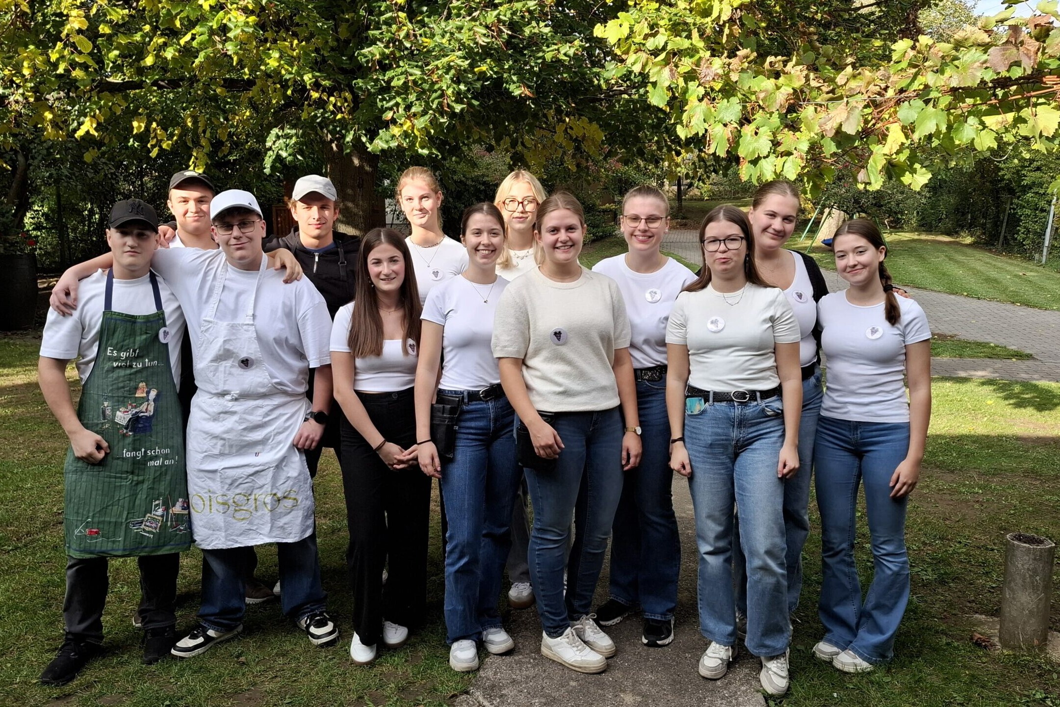 Eine Gruppe von Jugendlichen steht draußen gemeinsam für ein Gruppenfoto im Garten.